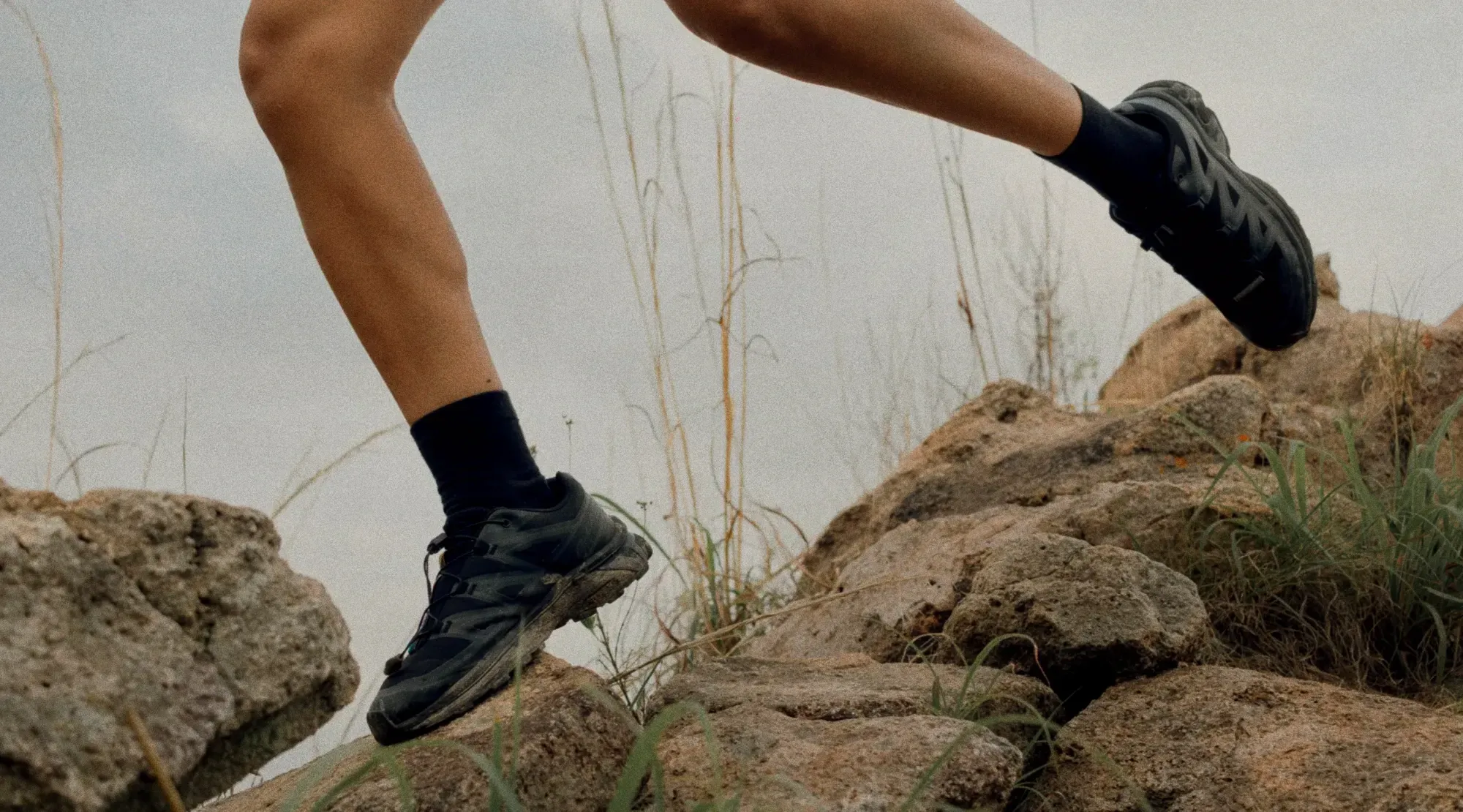 Trkač u crnim merino čarapama i patikama za trail skače preko stena